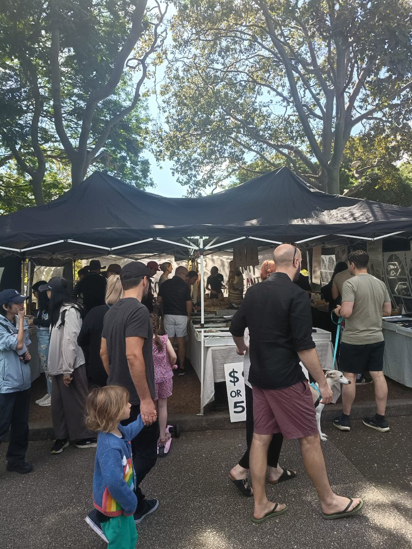 Customers visiting the Sargeantson market stall under trees at Brisbane farmers markets